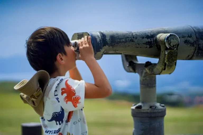 子どもが望遠鏡でのぞいているところ