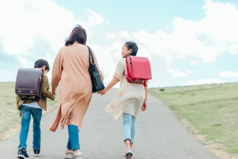 お母さんと小学生の子ども二人の後ろ姿